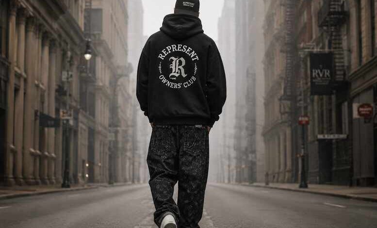 Flat-lay of a black stussy hoodie, white Amiri MA-1 sneakers, and a graphic mixed emotions shirt on a concrete floor.